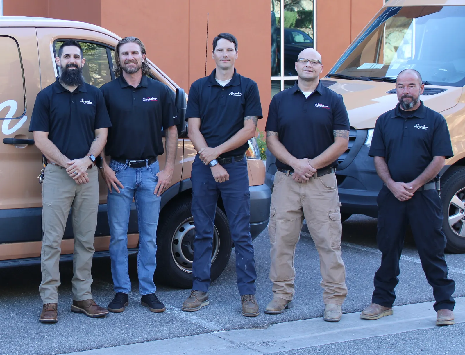 Kingdom Plumbing team, a Las Vegas plumber, between two branded service vans outside the office