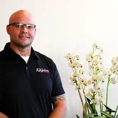 Kingdom Plumbing team member in glasses beside white orchids in the Las Vegas office
