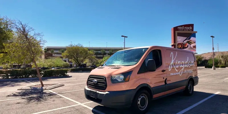 Peach Kingdom Plumbing van facing left in the Red Rock Casino lot with the resort spa pylon, hedges, and parking garage under a clear sky